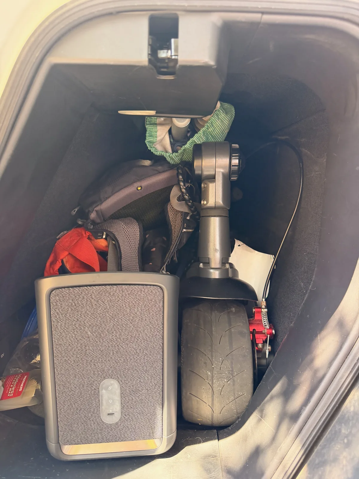 The Rivian R1T's gear tunnel packed with a folding electric scooter, a portable power station, charging cables, and bags