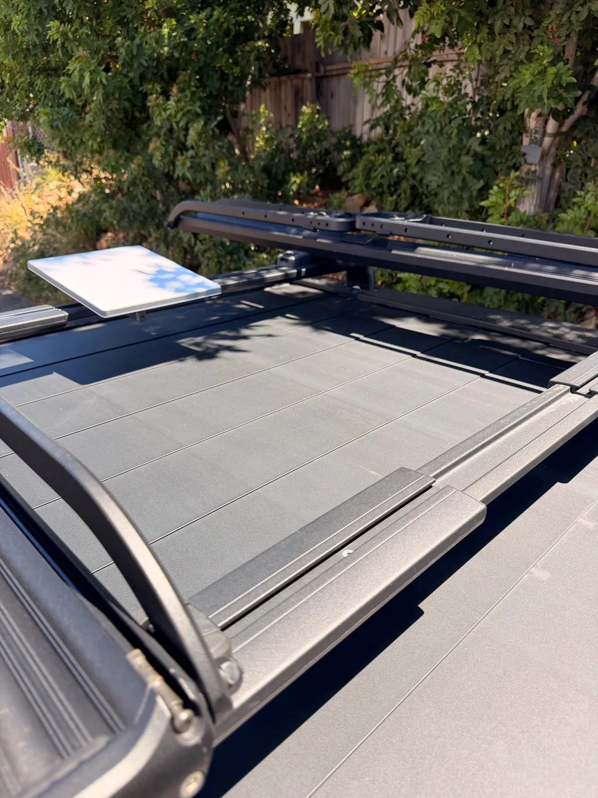 Looking down on the Rivian R1T's roof rack and powered tonneau cover with a flat solar panel mounted, ready for the long haul