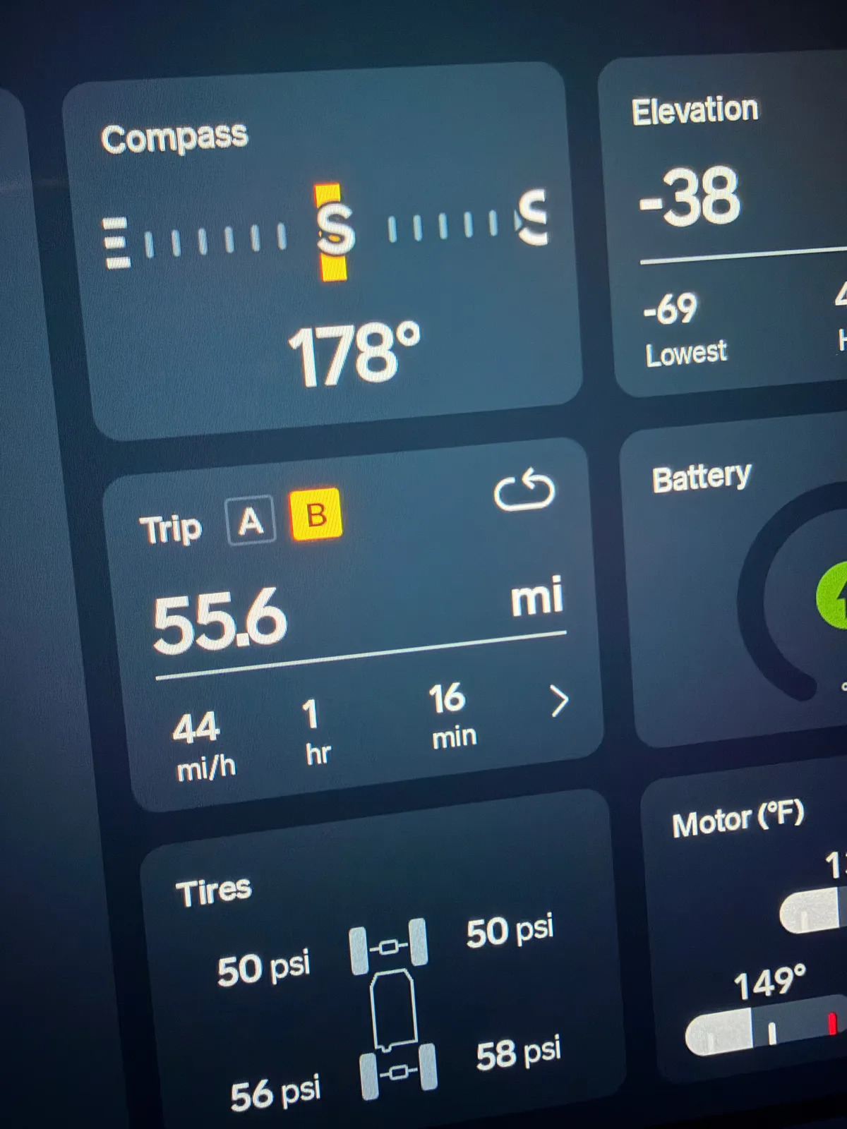 The Rivian R1T's center display showing the leg's trip readout at the El Centro charger, compass 178 degrees south, elevation -38 feet with a low of -69 feet, 55.6 miles at 44 mph average over 1 hour 16 minutes, plus tire pressures