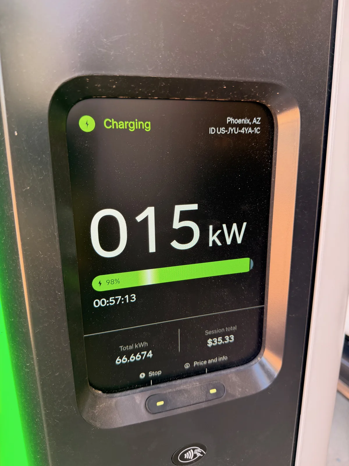 A Rivian Adventure Network pedestal screen at the Camelback Esplanade in Phoenix showing a "Charging" status, 015 kW, 98 percent state of charge, a 00:57:13 session time, 66.6674 total kWh delivered, and a $35.33 gross session total before the Rivian complimentary discount, with charger ID US-JYU-4YA-1C in the corner