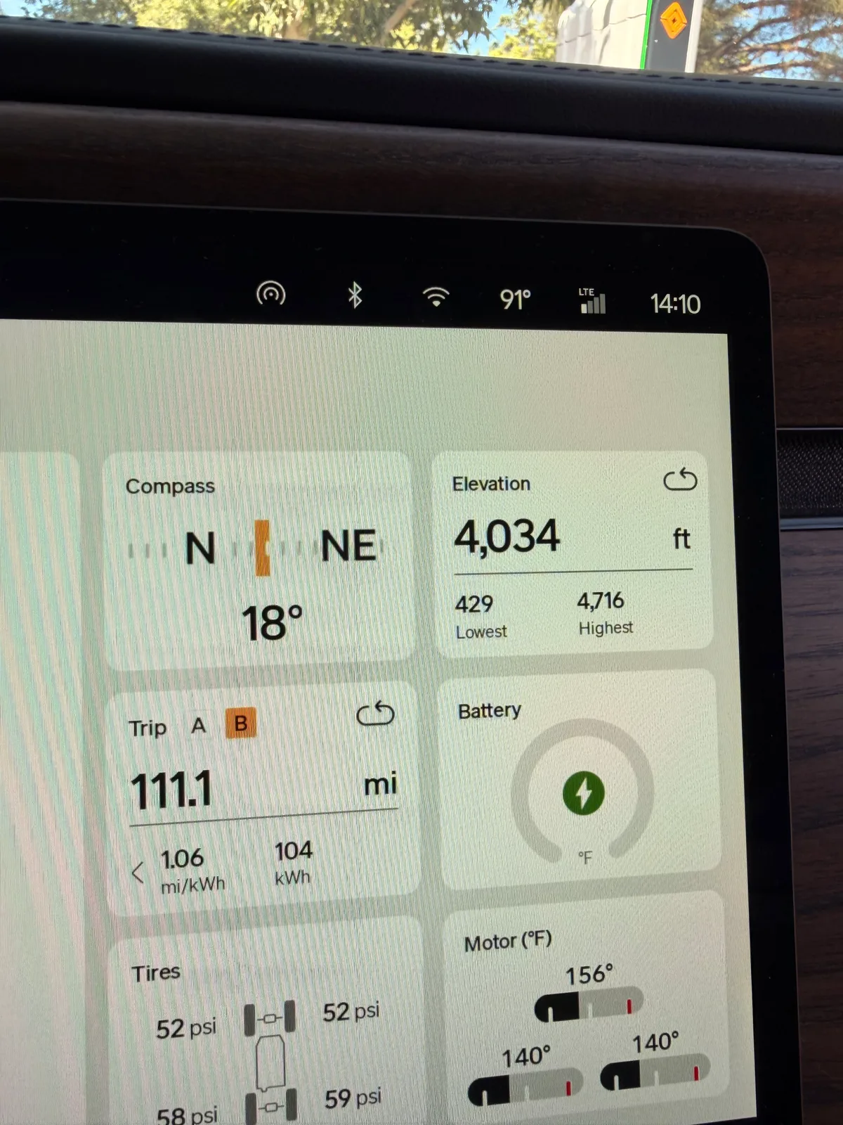 The Rivian R1T center display at the Sedona RAN showing Trip B 111.1 miles at 1.06 mi/kWh, 104 kWh used, elevation 4,034 ft (lowest 429, highest 4,716), compass NE 18 degrees, battery temperature 156°F (very hot), motor temps 140°F