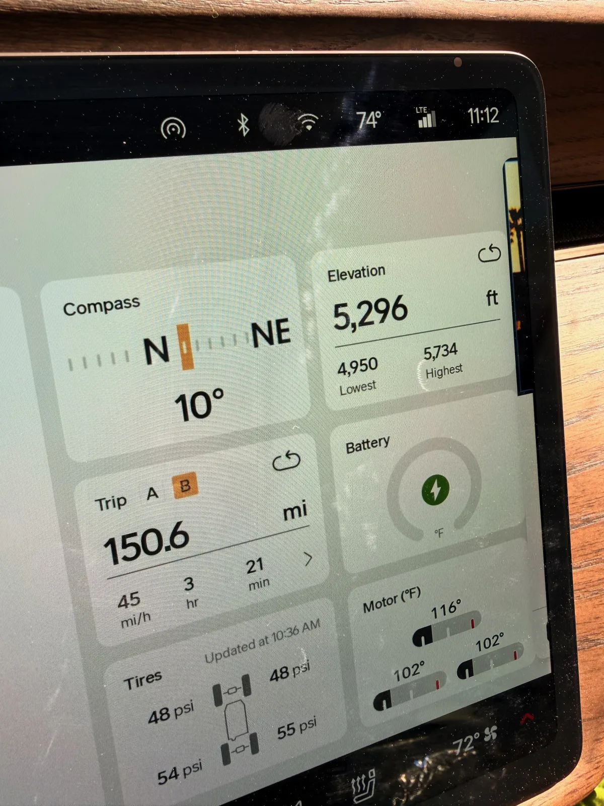 The Rivian R1T center display at the Uptown RAN at 11:12 AM during charging showing Trip B 150.6 miles at 45 mph over 3 hours 21 minutes, elevation 5,296 ft (lowest 4,950, highest 5,734), motor temps 100 to 116°F, battery charging