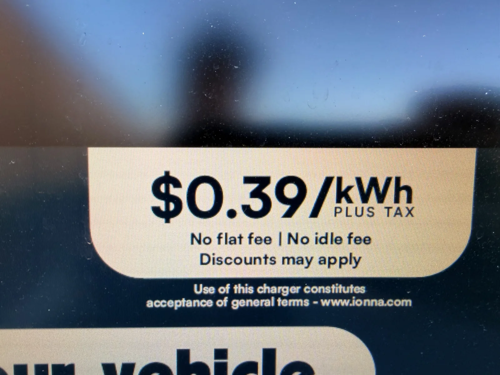 The IONNA pricing card on the side of the pedestal cabinet showing $0.39 per kWh plus tax, no flat fee, no idle fee, discounts may apply, with a "Use of this charger constitutes acceptance of general terms" note linking to www.ionna.com
