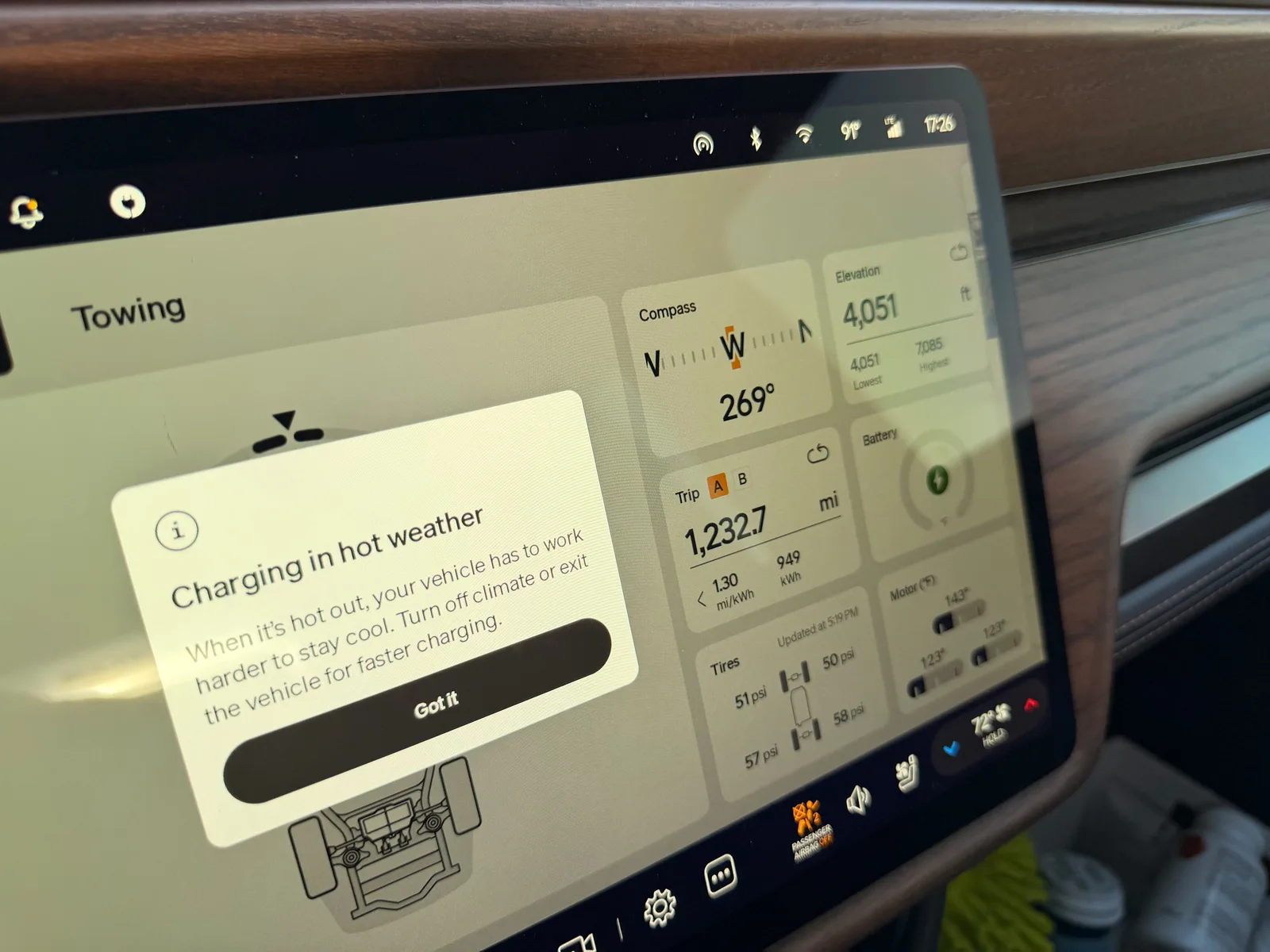 The Rivian R1T center display showing a "Charging in hot weather" advisory popup, with Trip A 1,232.7 miles at 1.30 mi/kWh and 949 kWh visible behind, motor temps 140 to 143°F, battery 100°F, ambient 93°F at Tucumcari IONNA
