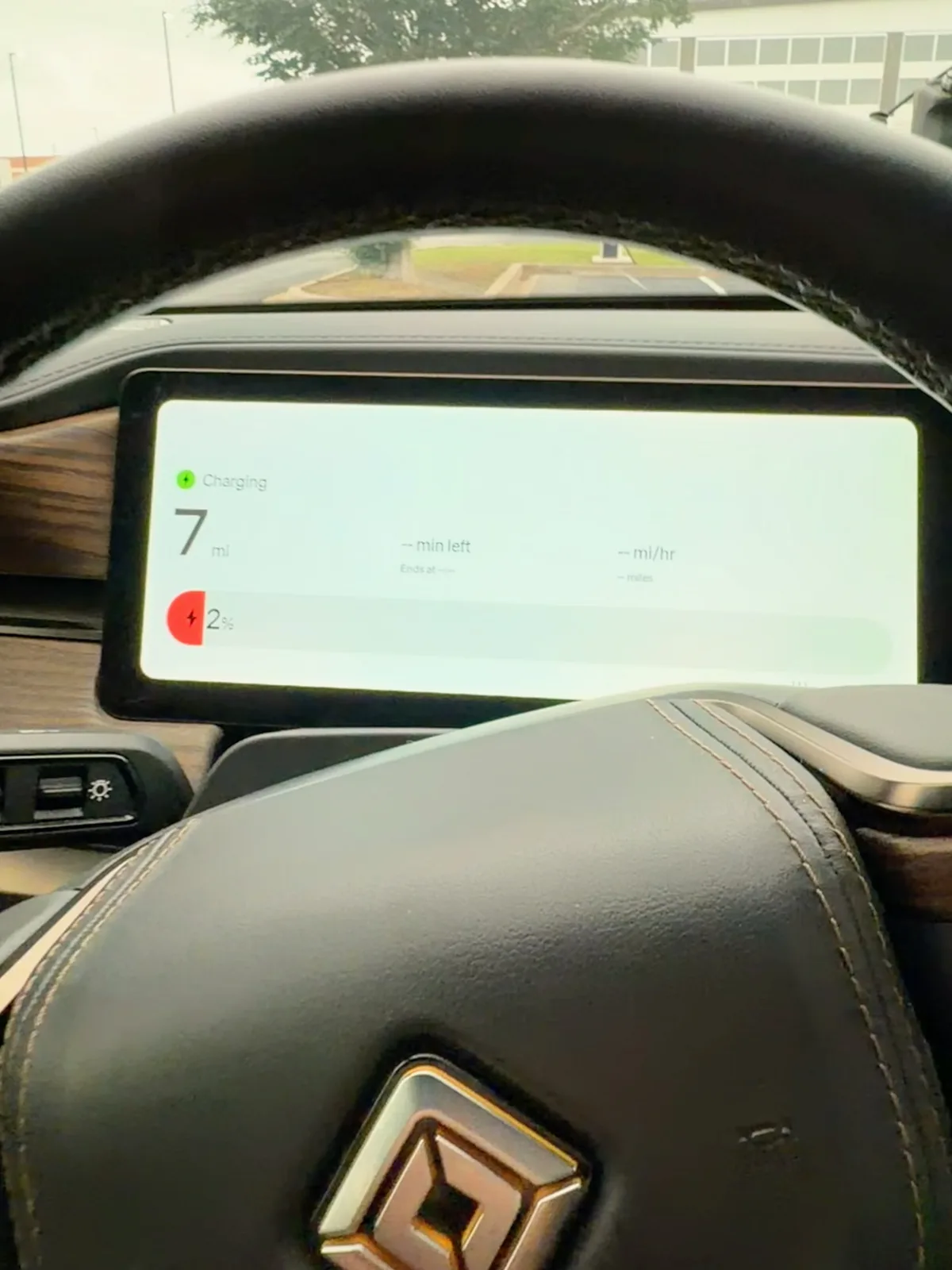 The Rivian R1T driver-side cluster gauge at the OKC RAN at 5:24 PM CDT showing Charging icon, 7 miles of range remaining, 2 percent state of charge as the rig plugged in at the most aggressive pack-low arrival of the trip