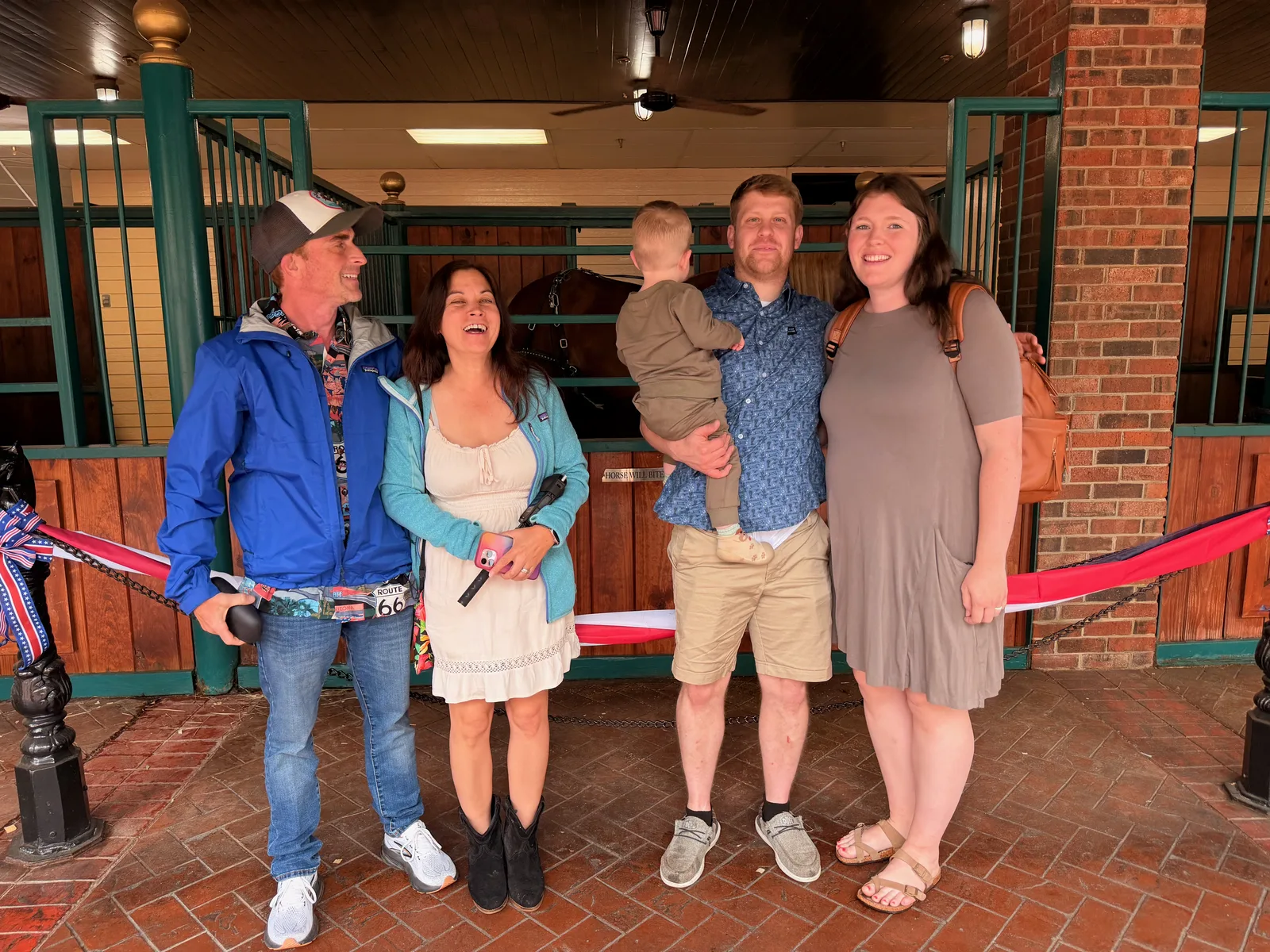 Eric and Diana with two friends posed in front of the Dolly Parton's Stampede entrance, a brick wall and red rope barrier behind them, before the evening show