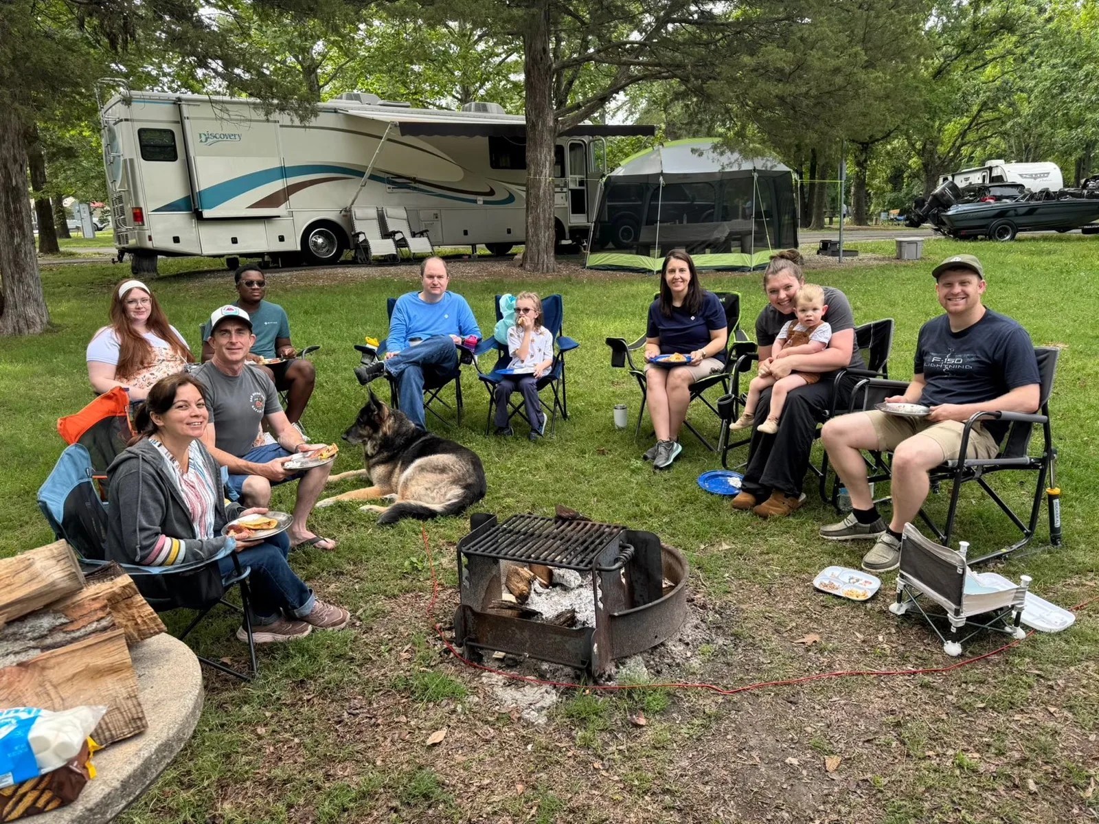 The EV-meetup group gathered in camp chairs around the fire ring at the Indian Point campsite, their RVs and rigs parked behind under the trees