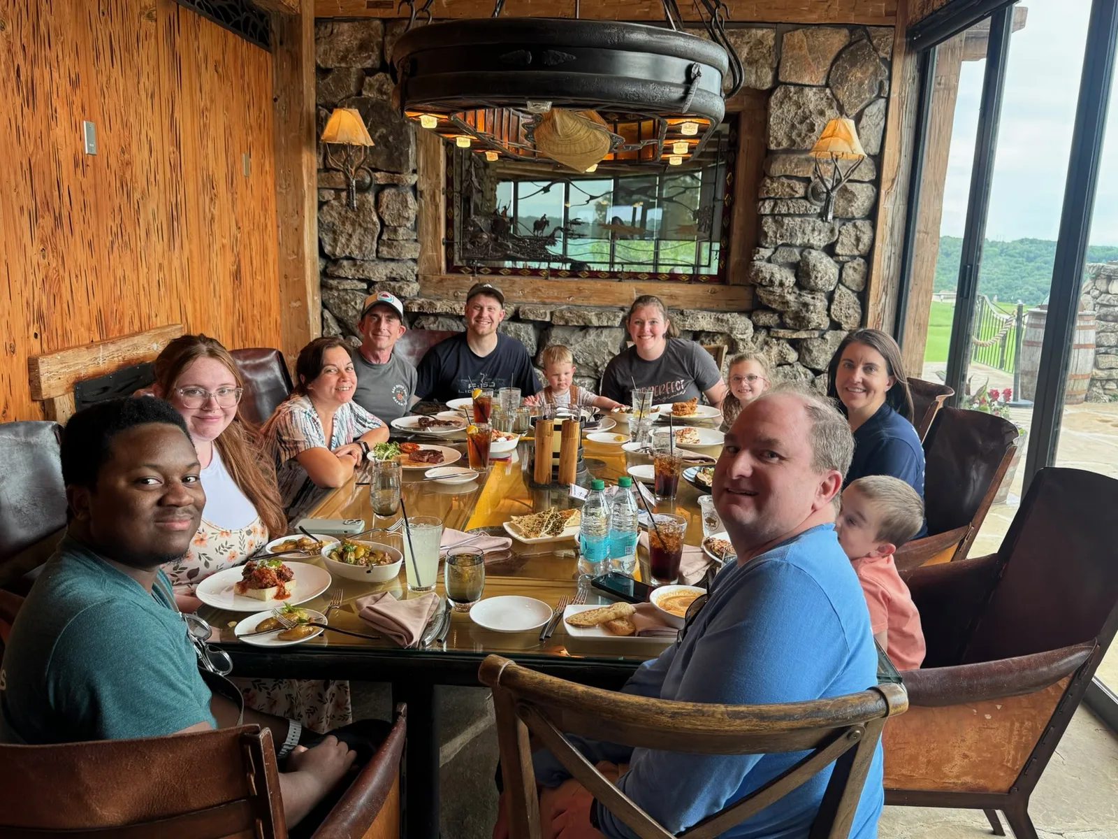The group around the dinner table at Osage Restaurant at Big Cedar Lodge, plates and drinks out in the warm stone-and-timber dining room