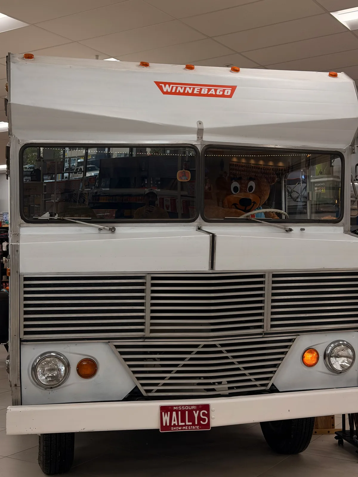 A vintage white Winnebago motorhome with a WALLY'S front license plate parked on display at the Fenton travel center