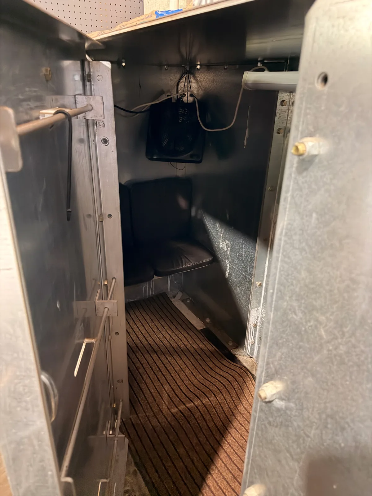 The interior of a steel TornadoSafeRoom storm shelter, corrugated metal walls and a small vent at the top, ready for a midwest summer storm