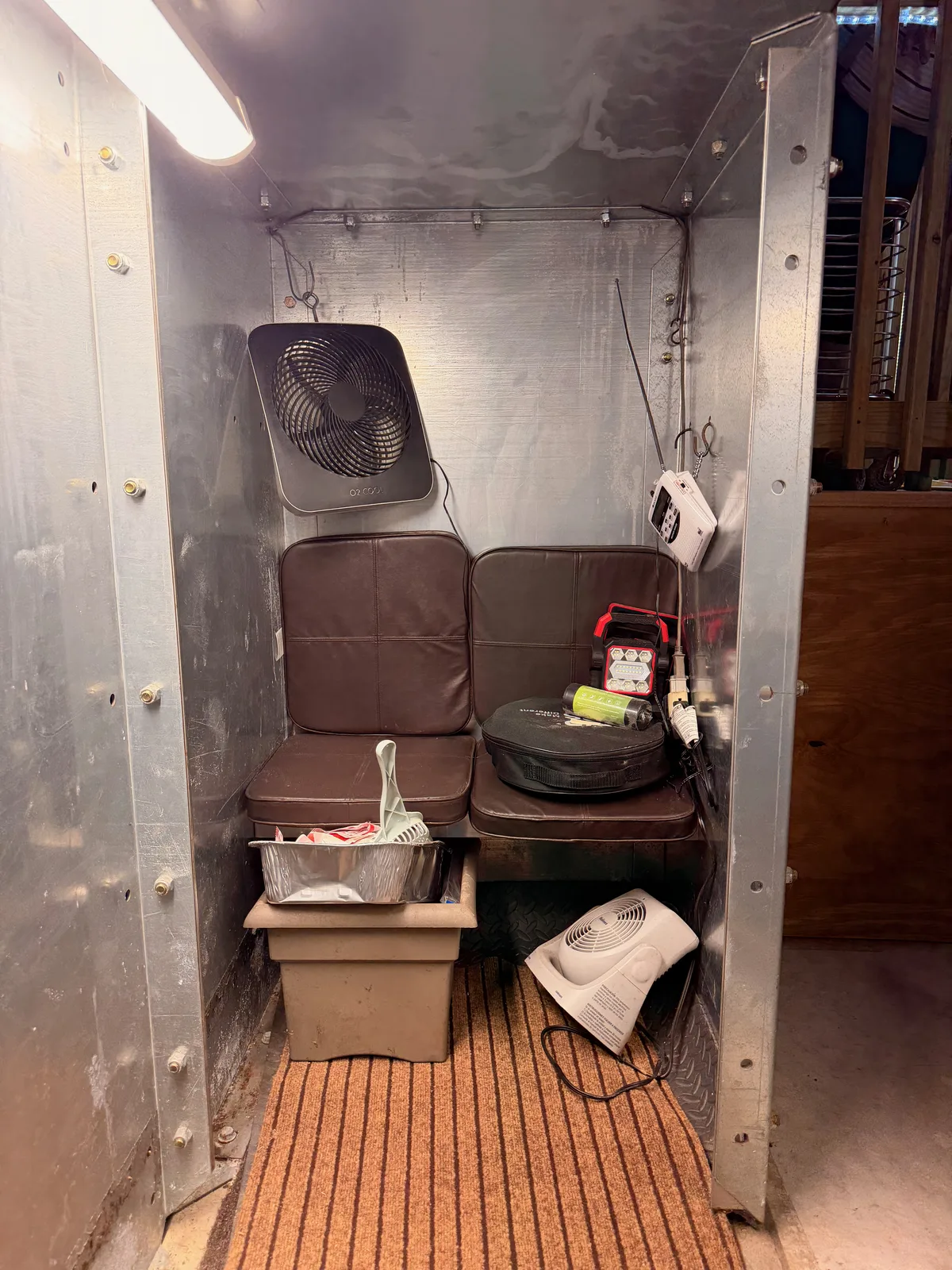Folding chairs and a bin of emergency supplies stored inside a steel TornadoSafeRoom storm shelter, the floor mat down and ready