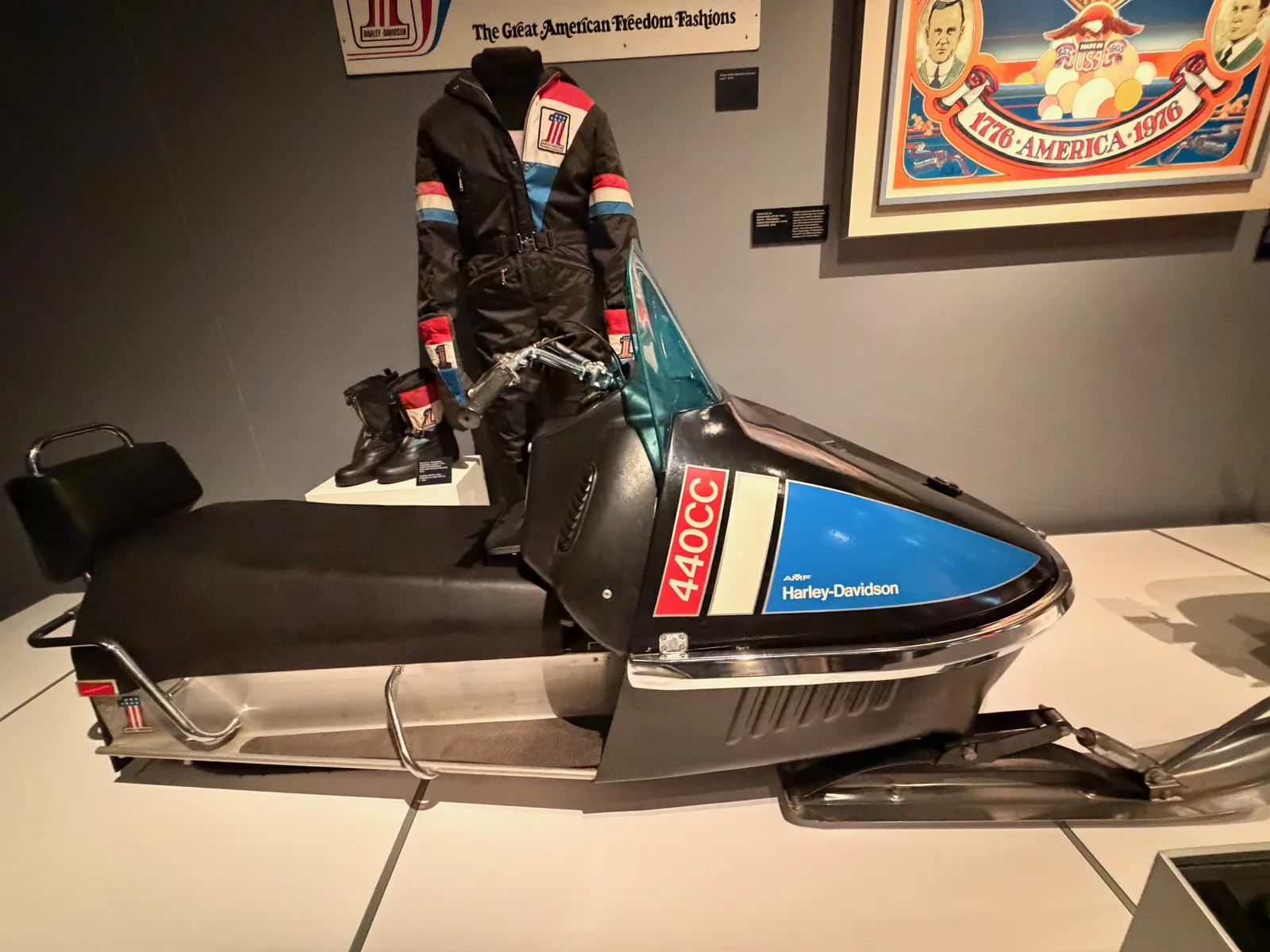 A 1970s AMF-era Harley-Davidson 440 snowmobile and a red-white-and-blue freedom-fashions snowmobile suit on display in the Harley-Davidson Museum