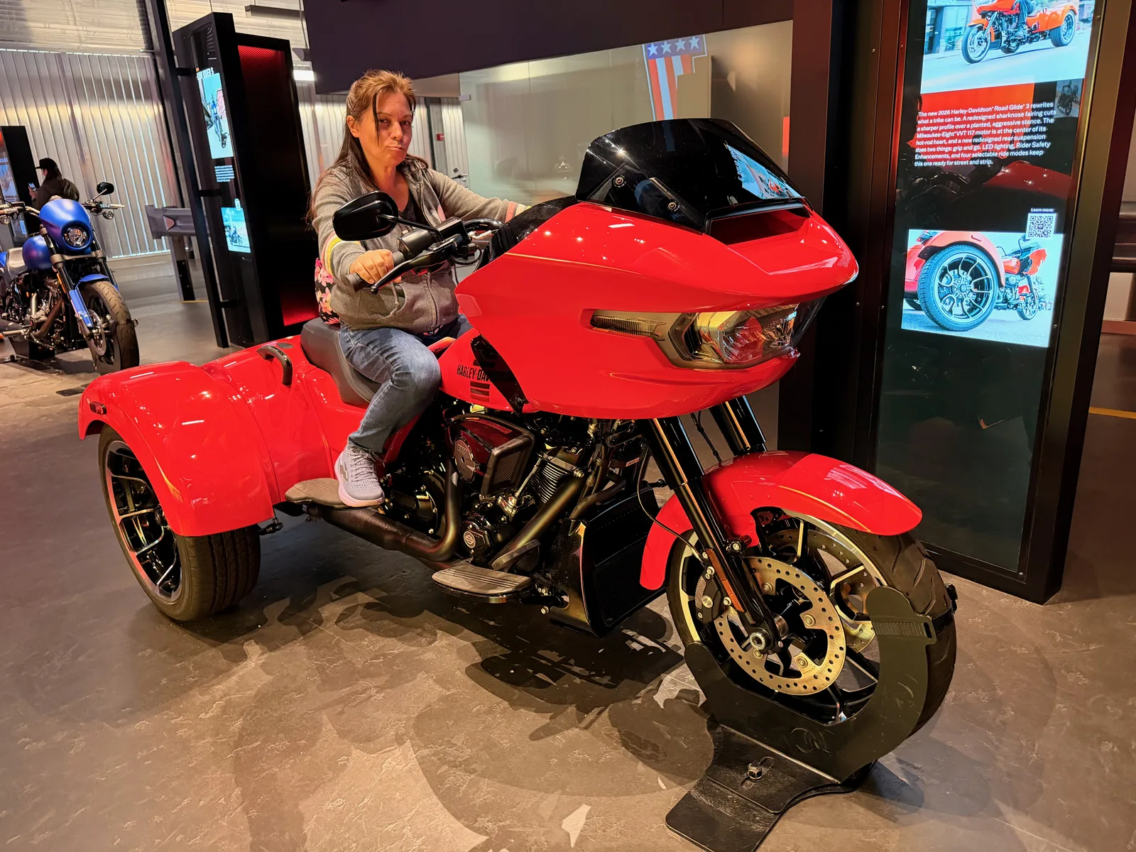 Diana sitting on a new red Harley-Davidson Road Glide 3 trike in the sit-on Experience Gallery at the Harley-Davidson Museum