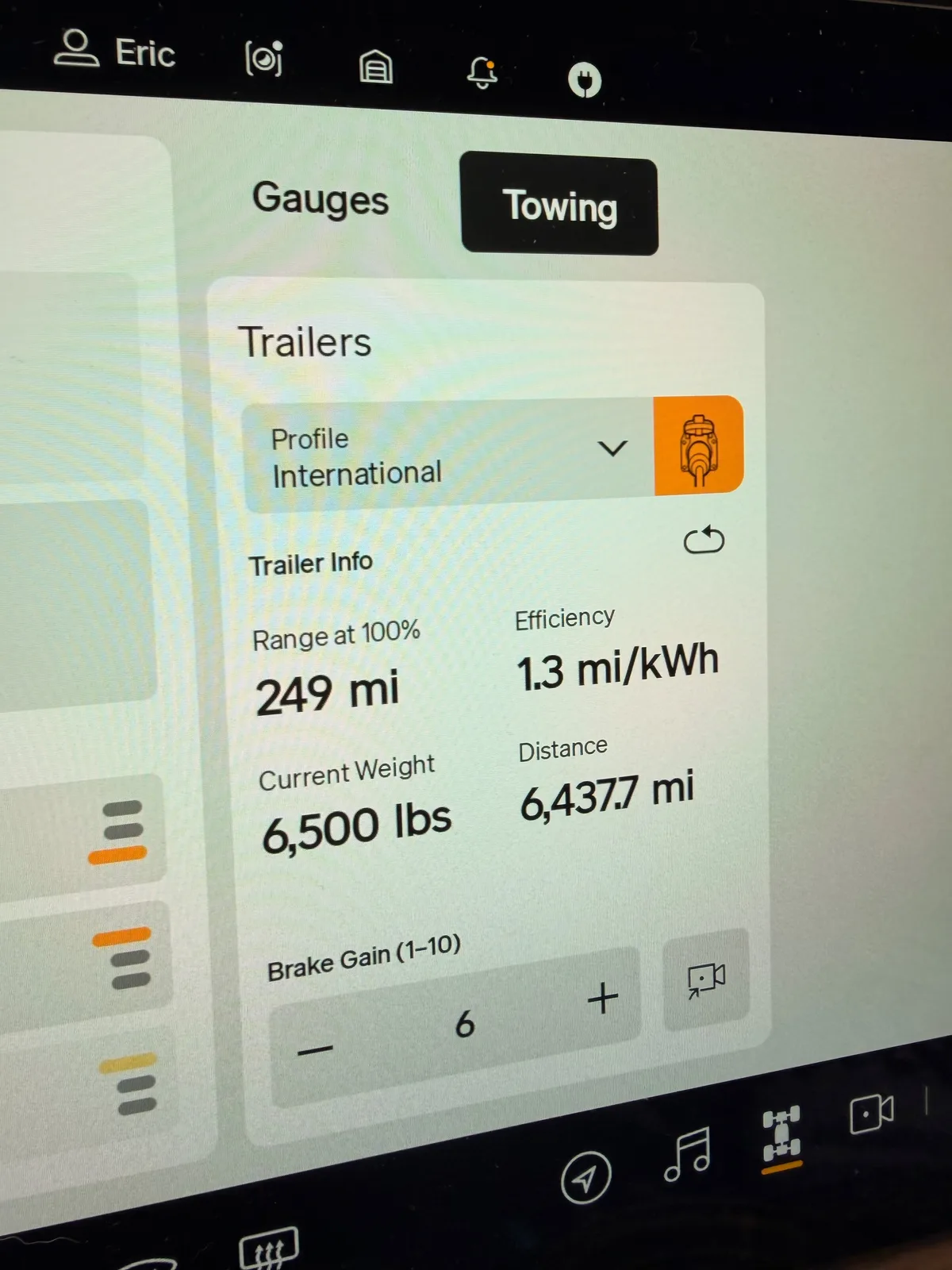 The Rivian R1T towing screen showing the International trailer profile, 249 miles range at 100 percent, 1.3 mi/kWh efficiency, current weight 6,500 lbs, brake gain 6
