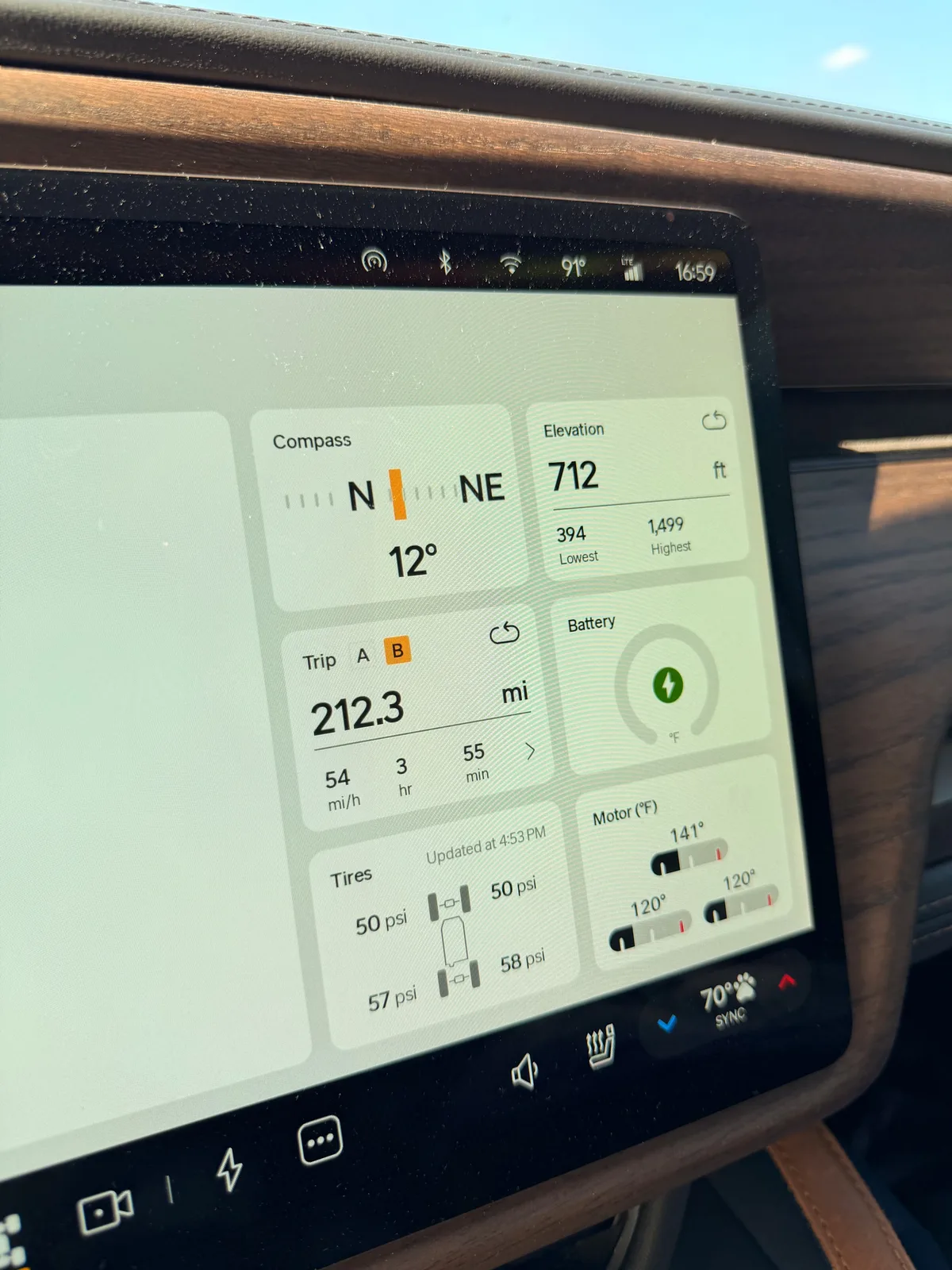 The Rivian R1T center display at the Mount Pleasant Supercharger showing Trip B 212.3 miles, compass NNE, elevation 712 feet, battery charging, 70 degrees F