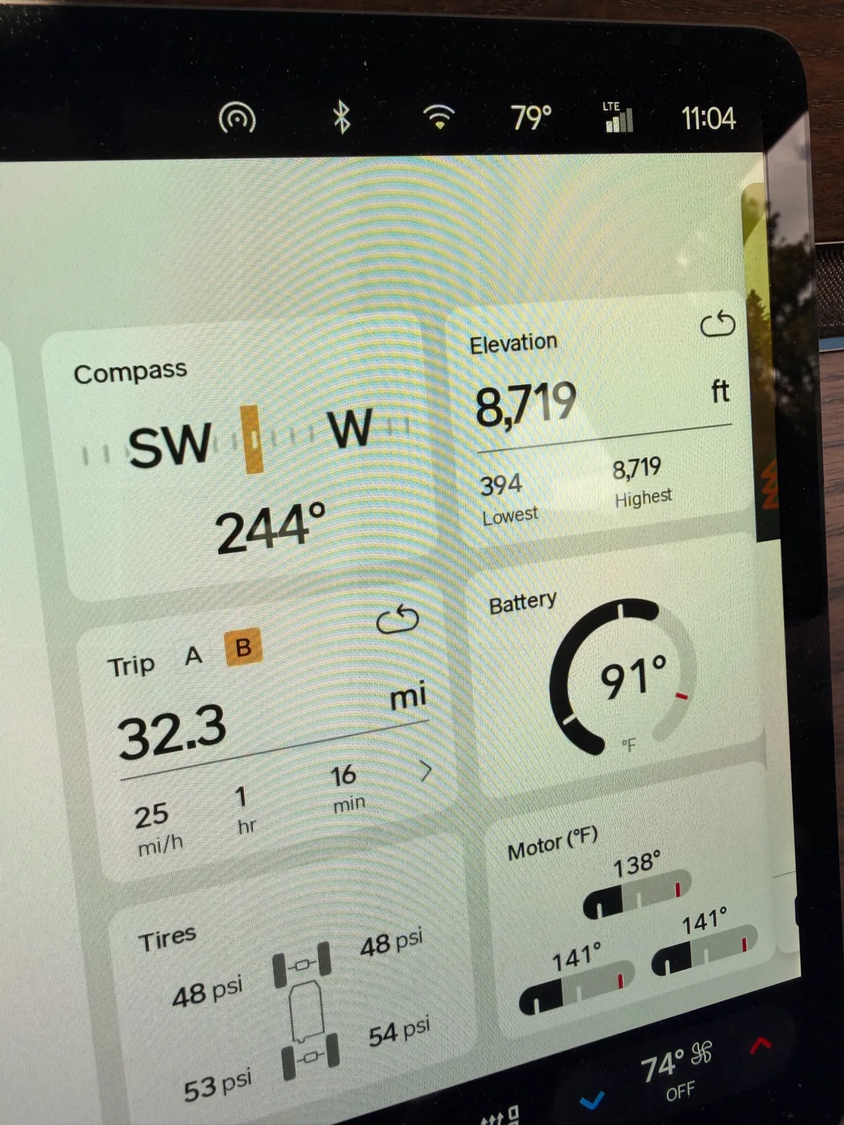 Rivian R1T center display entering Rocky Mountain National Park at 11:04 AM showing elevation 8,719 ft, Trip B 32.3 mi at 25 mph, battery 91 F, motor temps 138 to 141 F, tires 48 psi front and 53 to 54 psi rear, ambient 79 F