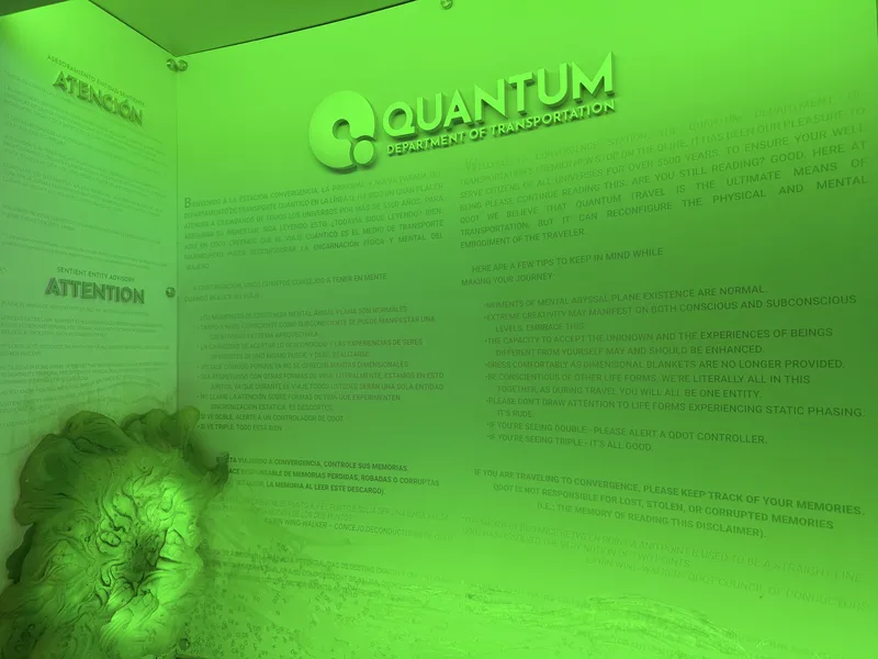 A glowing green immersive room inside Meow Wolf Convergence Station in Denver, the word QUANTUM lit on the wall