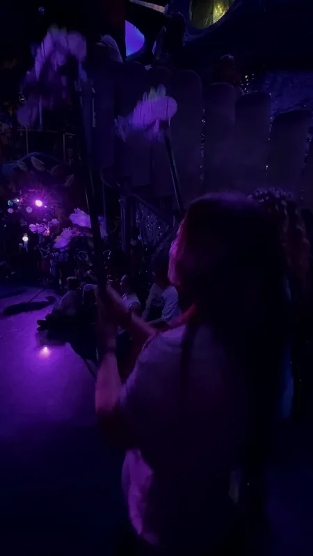 A dark room inside Meow Wolf Convergence Station lit electric purple, neon installations glowing in the low light