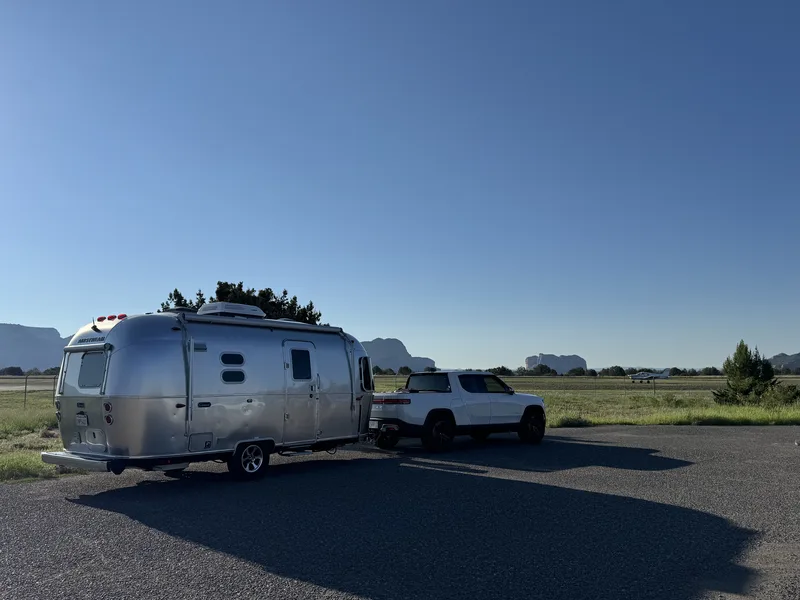 The Rivian R1T towing the 20-foot Airstream Caravel up a red-rock grade near Sedona, Arizona