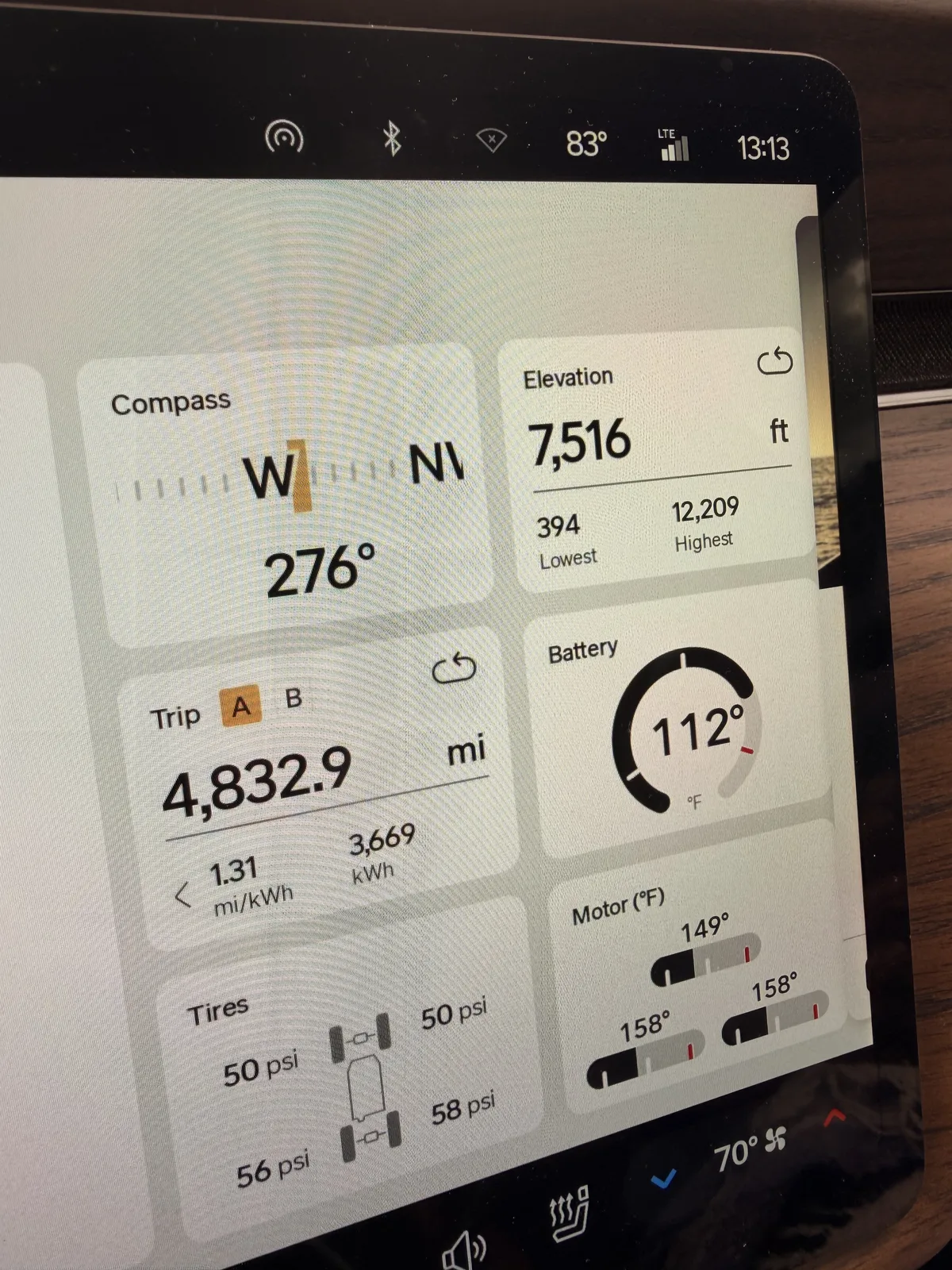 Rivian R1T center display towing on the I-70 climb at Idaho Springs at 1:13 PM showing Trip A 4,832.9 miles at 1.31 mi/kWh and 3,669 kWh trip-to-date, elevation 7,516 ft, battery 112 F, motor temps 149 to 158 F, tires 50 and 50 psi front and 56 and 58 psi rear, ambient 83 F