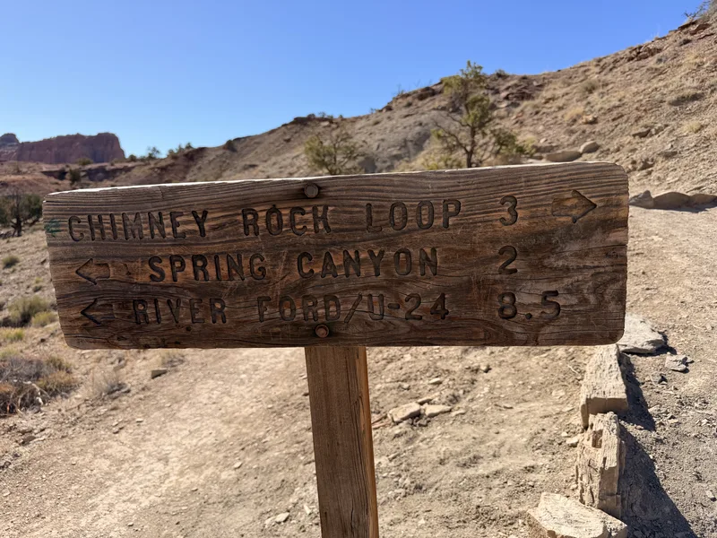 Wooden trail sign on the Chimney Rock Loop in Capitol Reef pointing to Spring Canyon and the UT-24 river ford