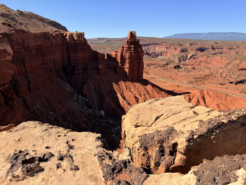 View from the Chimney Rock saddle in Capitol Reef, the red spire below with the gray-green Waterpocket country rolling out behind it