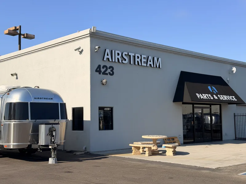 The silver Airstream beside the Airstream of San Diego building, the AIRSTREAM 423 lettering and a Parts and Service awning above the bay doors