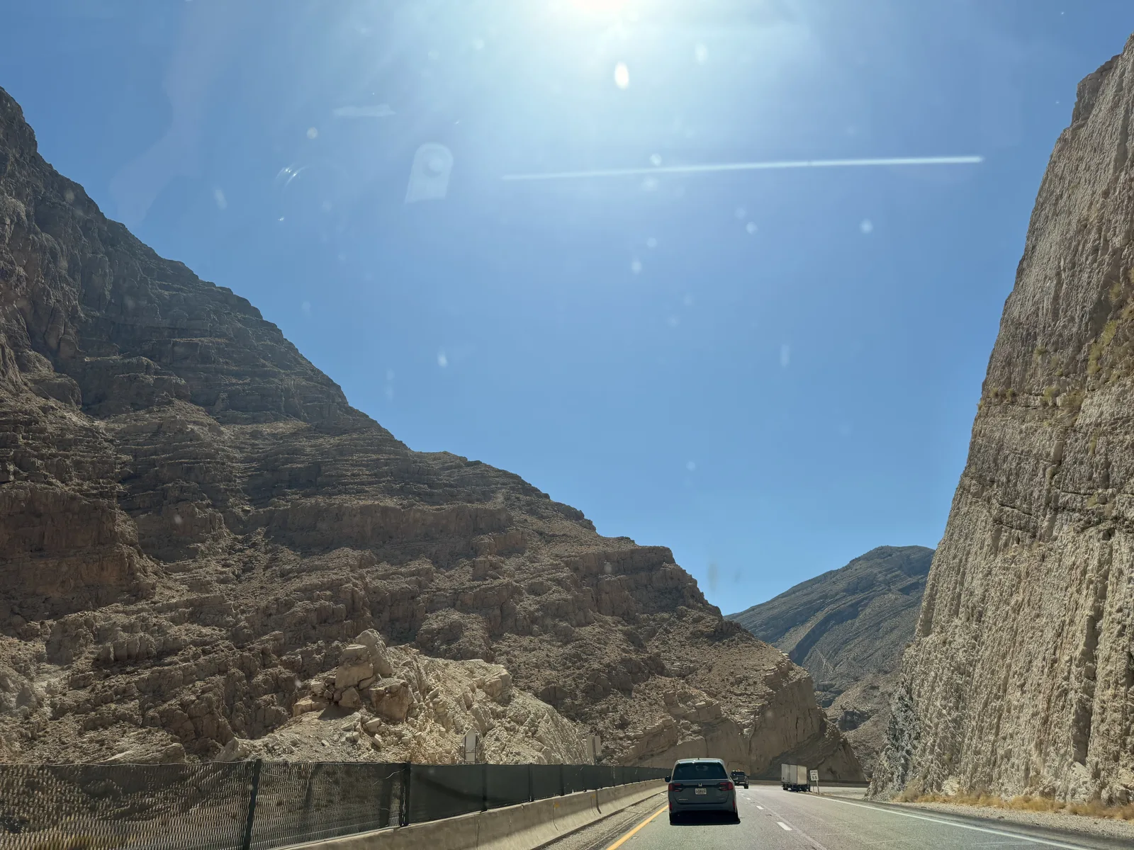 I-15 threading between towering tan canyon walls in the Virgin River Gorge, Arizona, traffic ahead under bright midday sun on the Utah Ducati Run