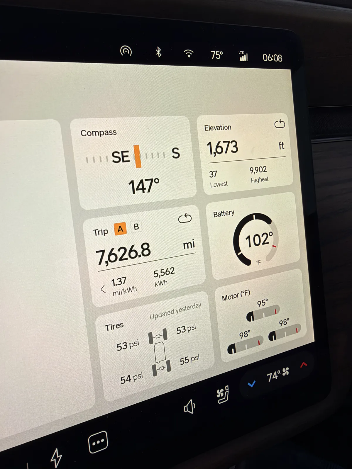 The Rivian R1T center display at dawn in Mesquite, Nevada showing Trip A 7,626.8 miles at 1.37 mi/kWh and 5,562 kWh cumulative, elevation 1,672 ft, battery 102°F, before the day's towed run home.