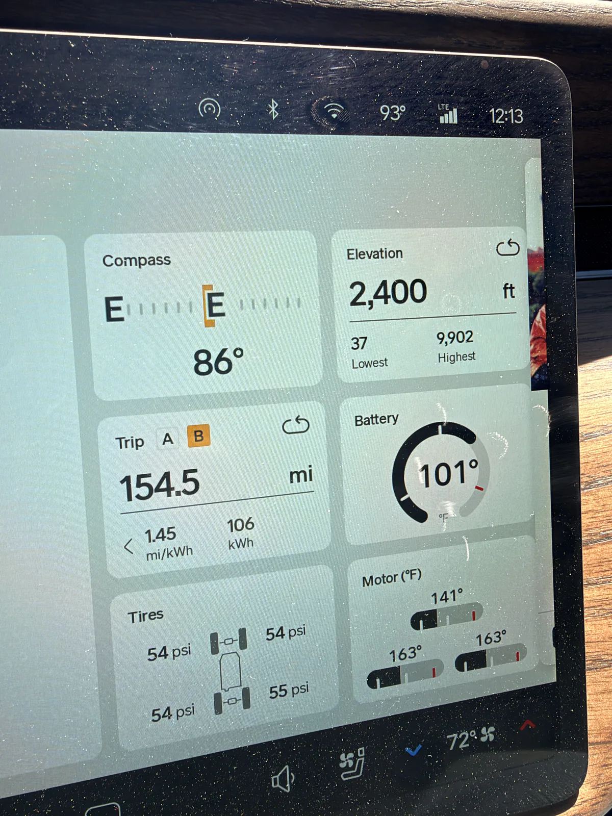 The Rivian R1T instrument display at Barstow, California showing Trip B 154.5 miles at 1.45 mi/kWh and 106 kWh, elevation 2,400 ft, motors 141 to 163°F, ambient 93°F, towing.