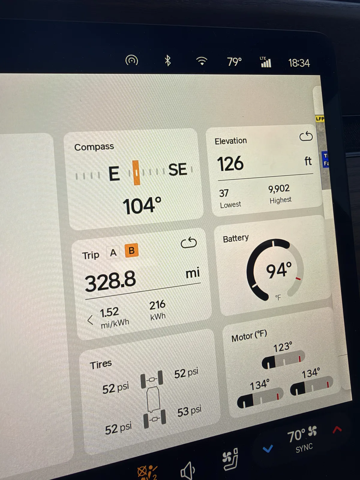 The Rivian R1T instrument display at the last charge in Orange County showing Trip B 328.8 miles at 1.52 mi/kWh and 216 kWh, elevation 126 ft, motors 123 to 134°F, towing, near sea level on the coast.