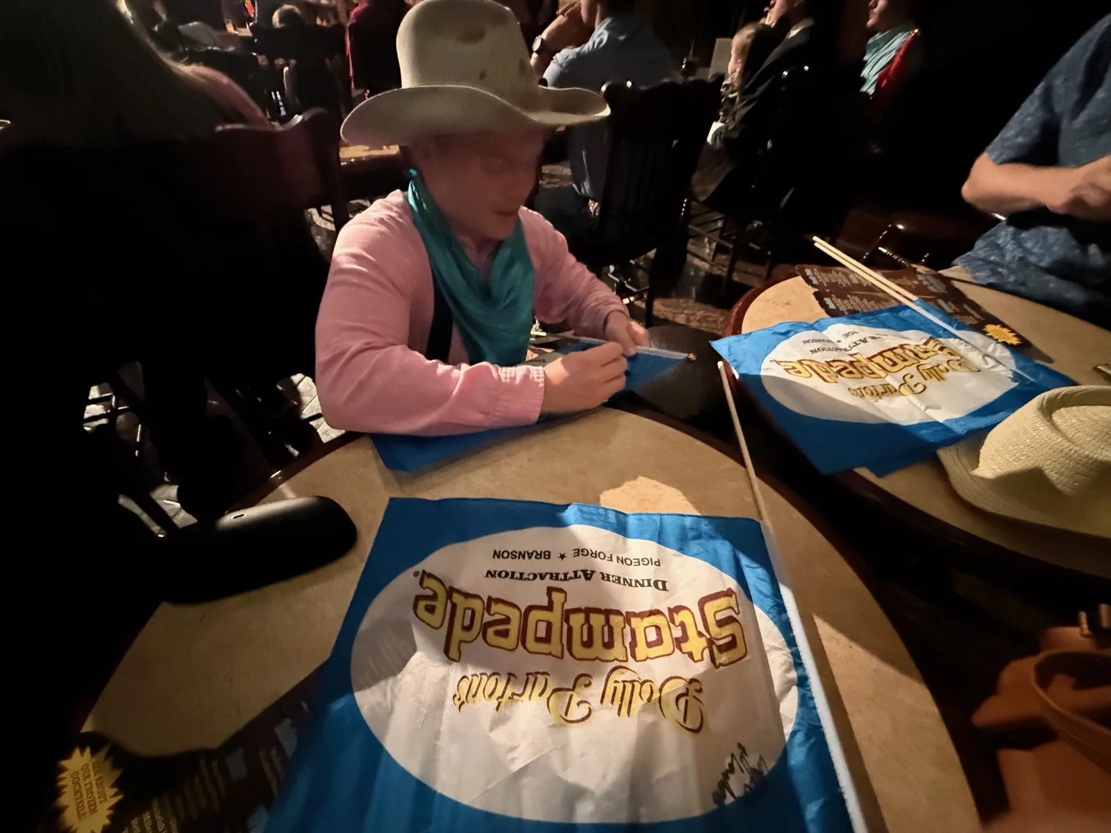 A diner in a cowboy hat at a table at Dolly Parton's Stampede with the signature platter, a whole rotisserie chicken and sides served with no silverware