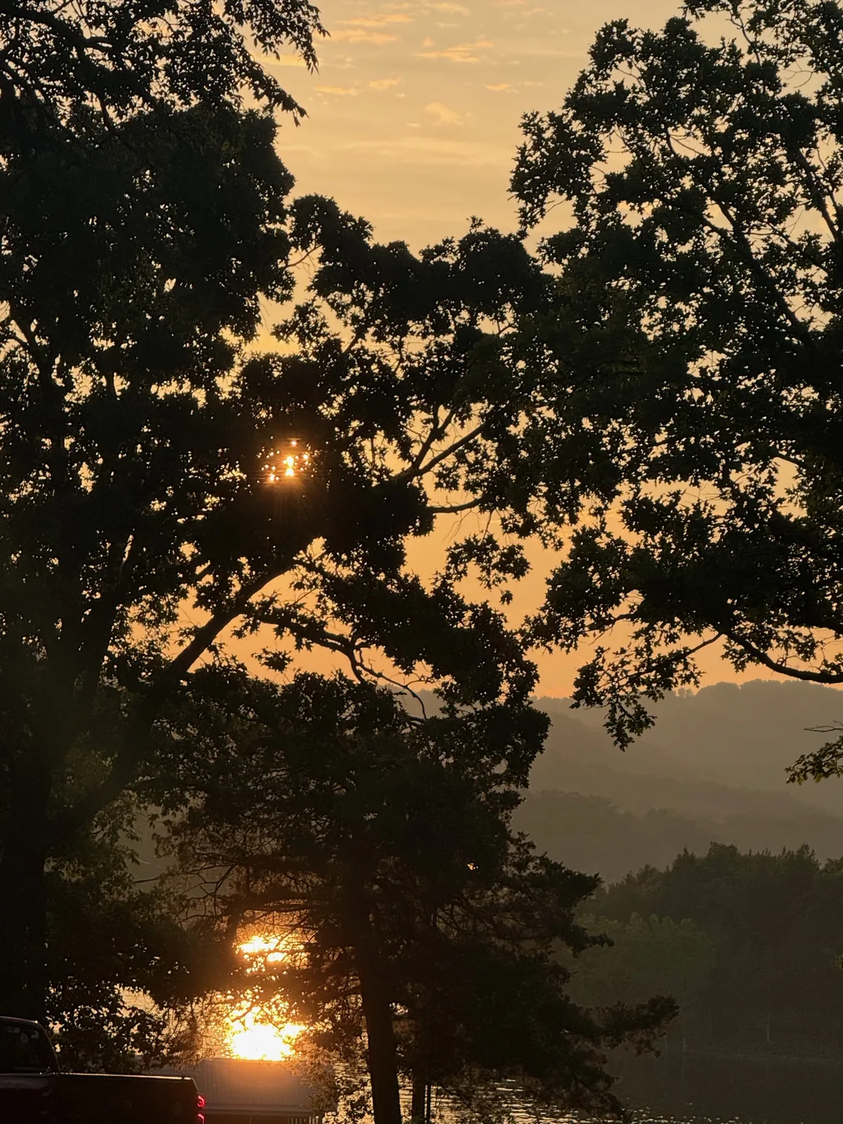Sunset through the trees at the Indian Point campsite, the sun a bright point low on the horizon over Table Rock Lake