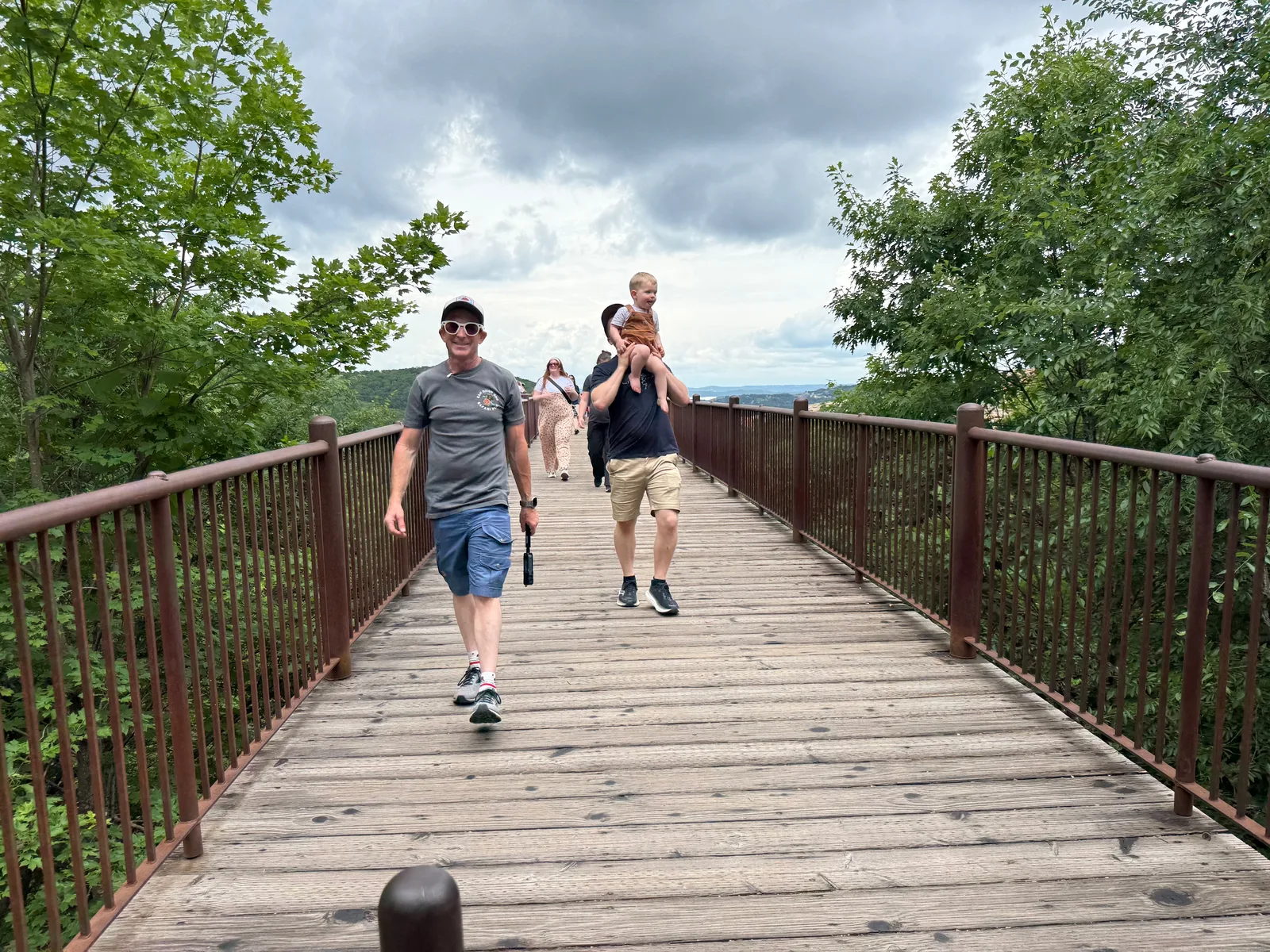 A long wooden boardwalk bridge winding through dense green Ozark woods on the Top of the Rock nature trail