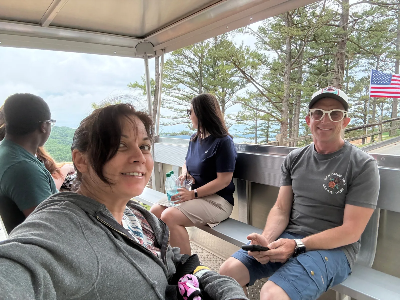 The dinner group together on the covered patio at Osage Restaurant, the Ozark view and an American flag behind them