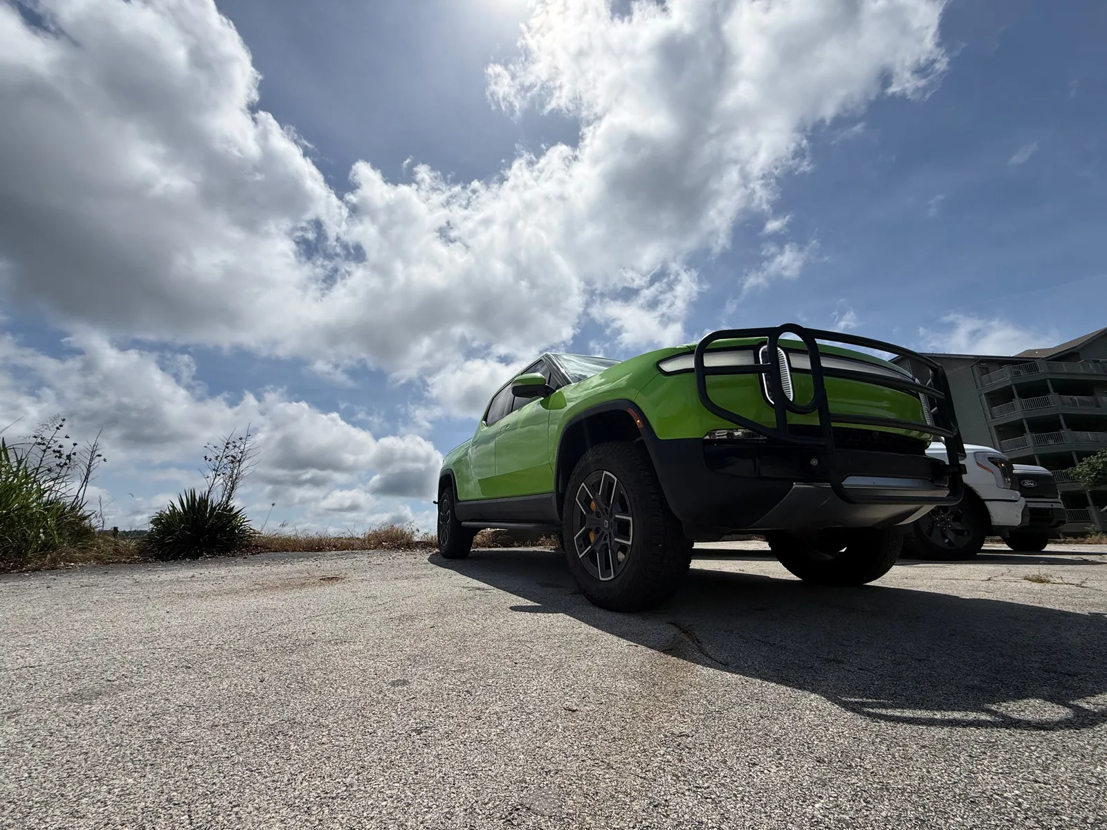 A dark green electric pickup parked at the Table Rock Lake overlook, lake and hills behind under a cloudy sky