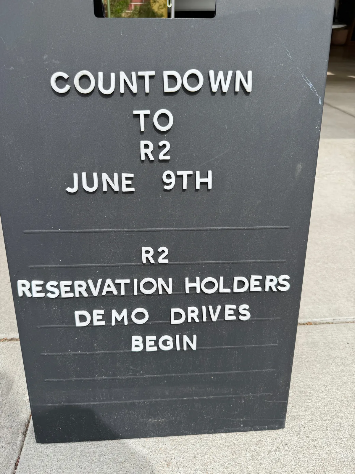 A sign at the Rivian Space reading Countdown to R2, June 9th, reservation holders demo drives begin