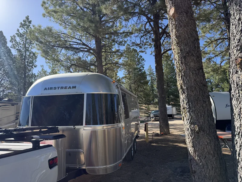 The polished Airstream hitched to the white Rivian R1T among the ponderosas at Ruby's Inn, ready to roll into Bryce Canyon