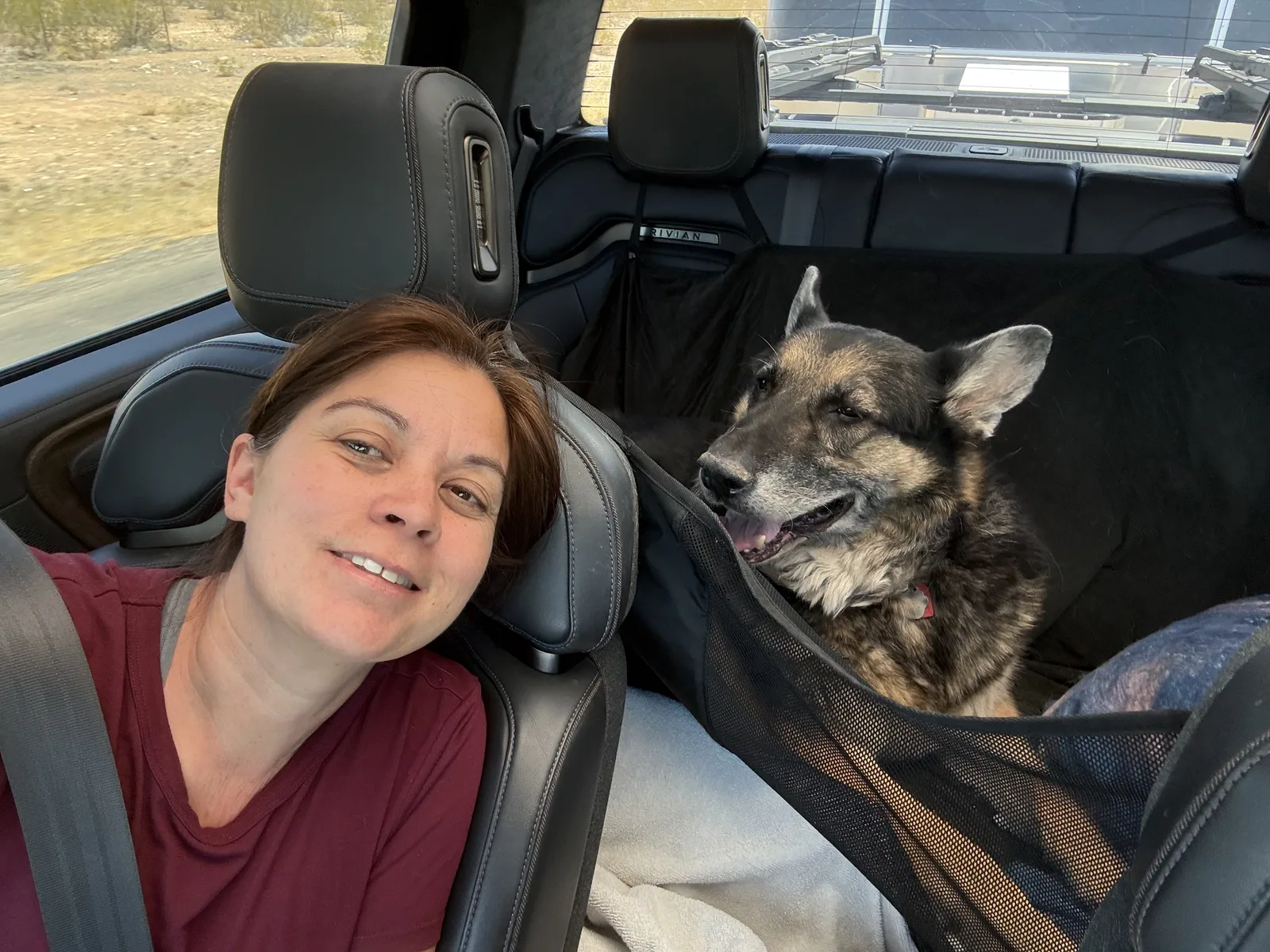 Diana in the front seat of the Rivian R1T with Mission, the older German Shepherd, riding in a back-seat hammock beside her
