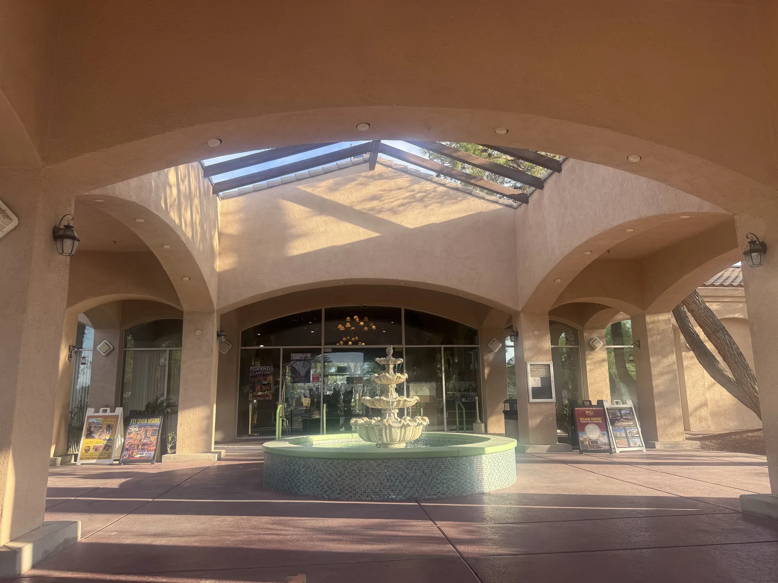 The arched stucco entrance portico and tiered fountain at the Oasis Las Vegas RV Resort lobby in afternoon light
