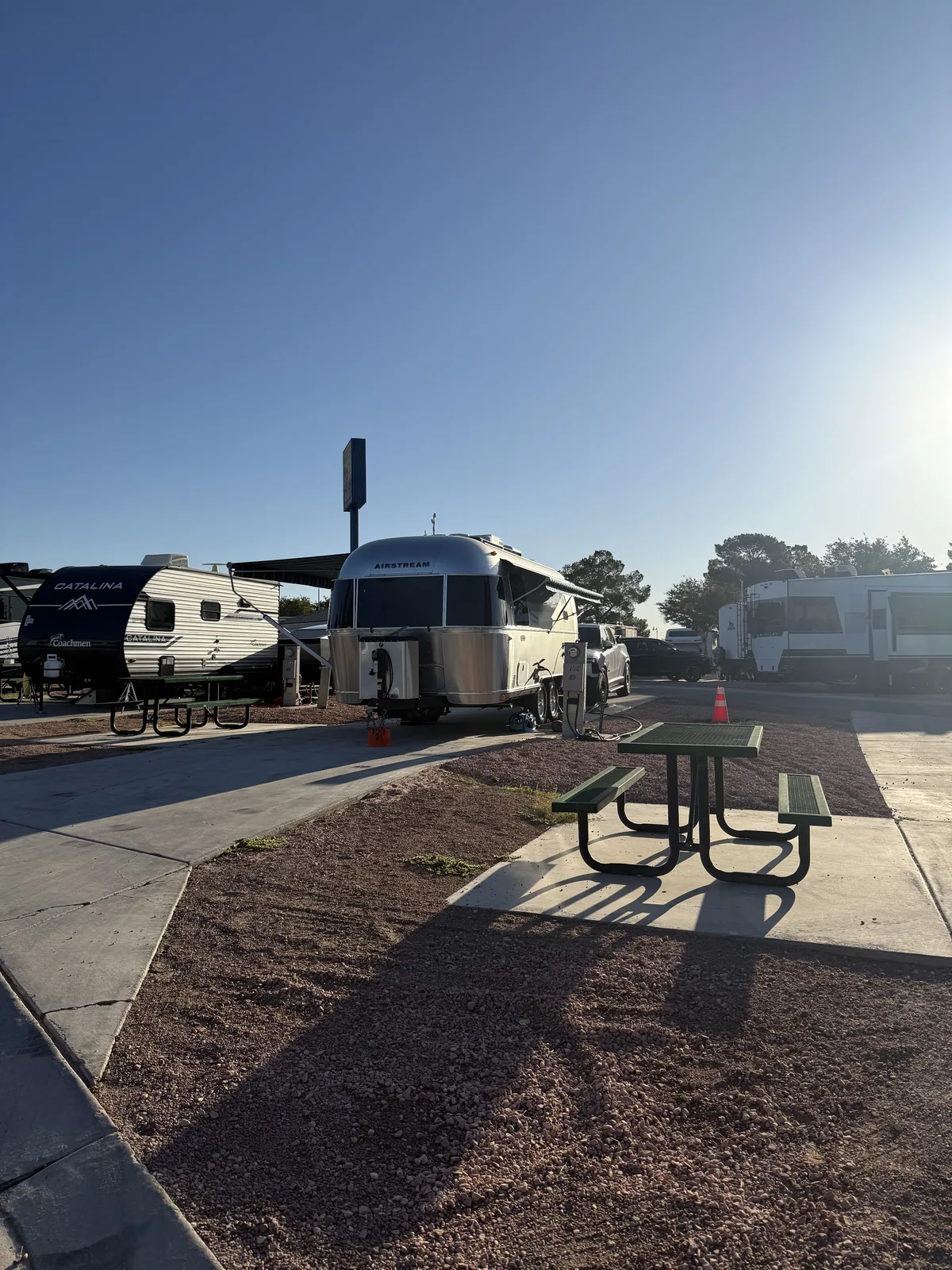 The polished Airstream and Rivian R1T lit gold by sunrise on the final morning of the trip at a Las Vegas RV resort