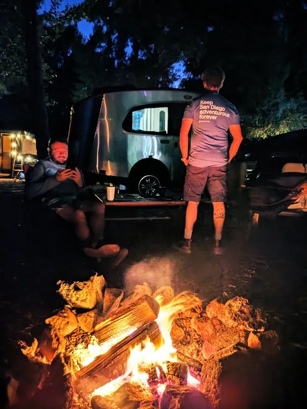 Campfire at dusk beside the 16-foot Airstream Basecamp, San Diego County, California, July 2024