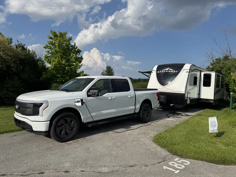 The Ford F-150 Lightning backed into campsite 185 beside the East to West Alta in warm evening light.