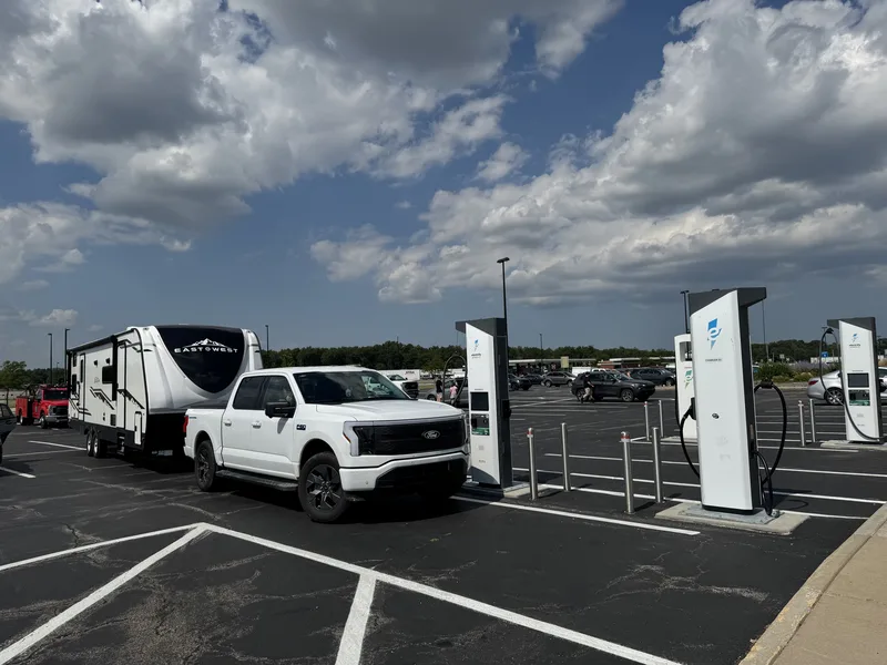The Ford F-150 Lightning and East to West Alta pulled through a bank of DC fast chargers under a mixed sky.