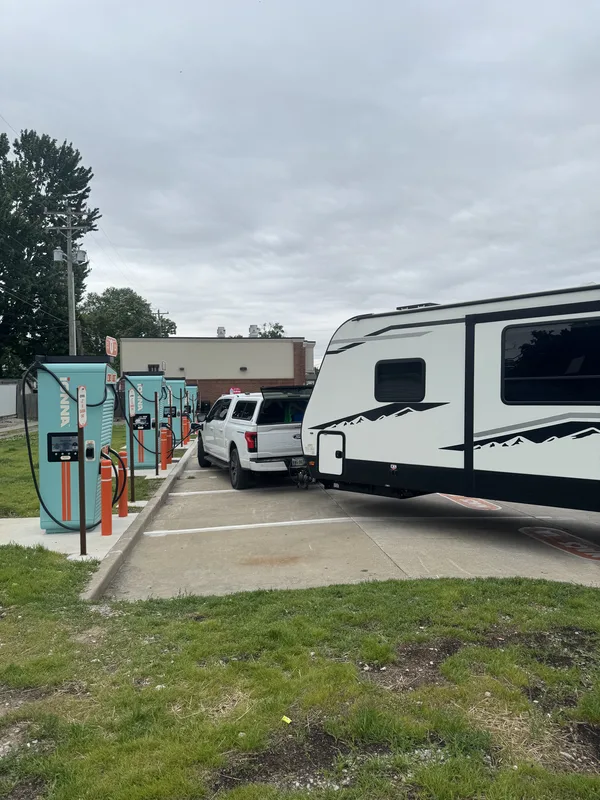 The Ford F-150 Lightning and East to West Alta pulled through a row of teal IONNA fast chargers on an overcast day.