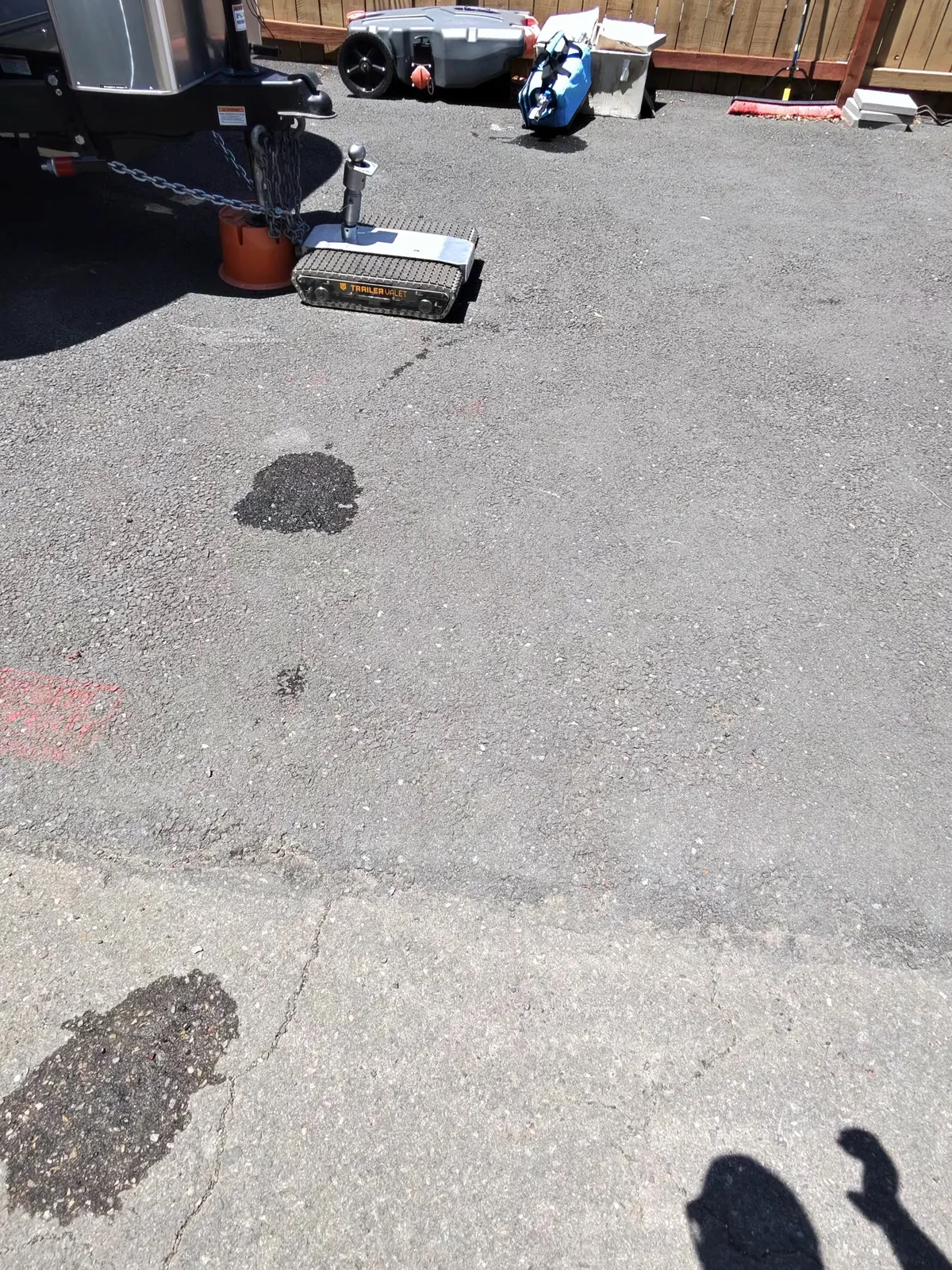 The Airstream tongue with the jack down on the asphalt at the storage lot, next to a Trailer Valet RVR motorized mover, about to be hitched up to the Rivian