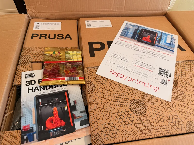 The opened Prusa CORE One box with the 3D printing handbook and packed components inside