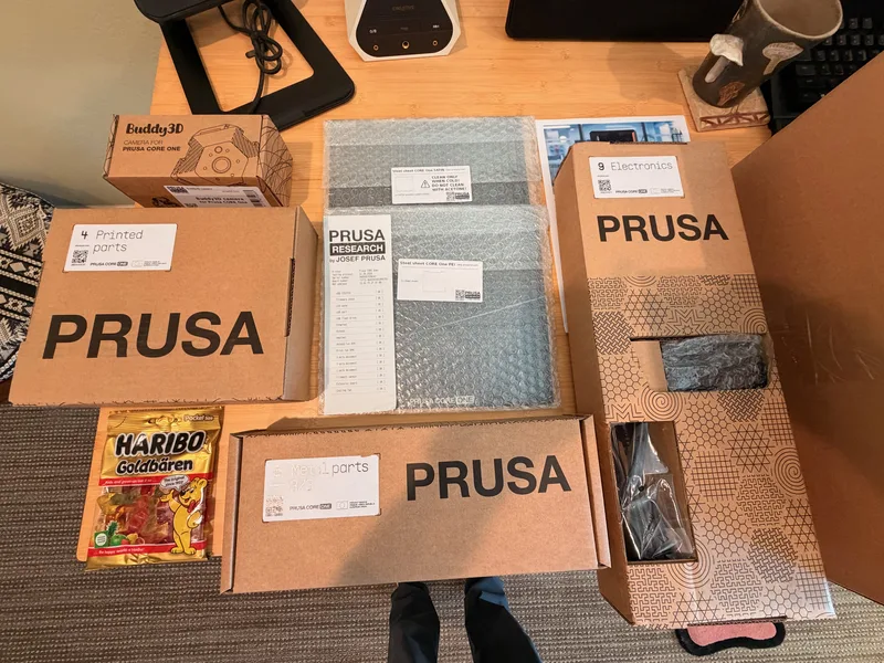 Prusa CORE One boxes and packaging spread across the assembly table