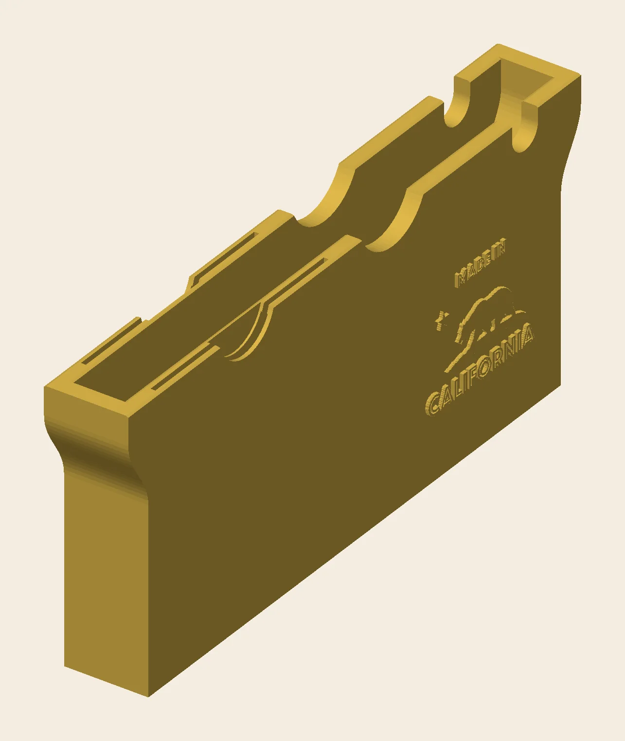 Gold CAD render of the Gold Wing center pocket phone cradle, phone slot facing up, with card pinch scoops, a USB notch, and a Made in California engraving on the face
